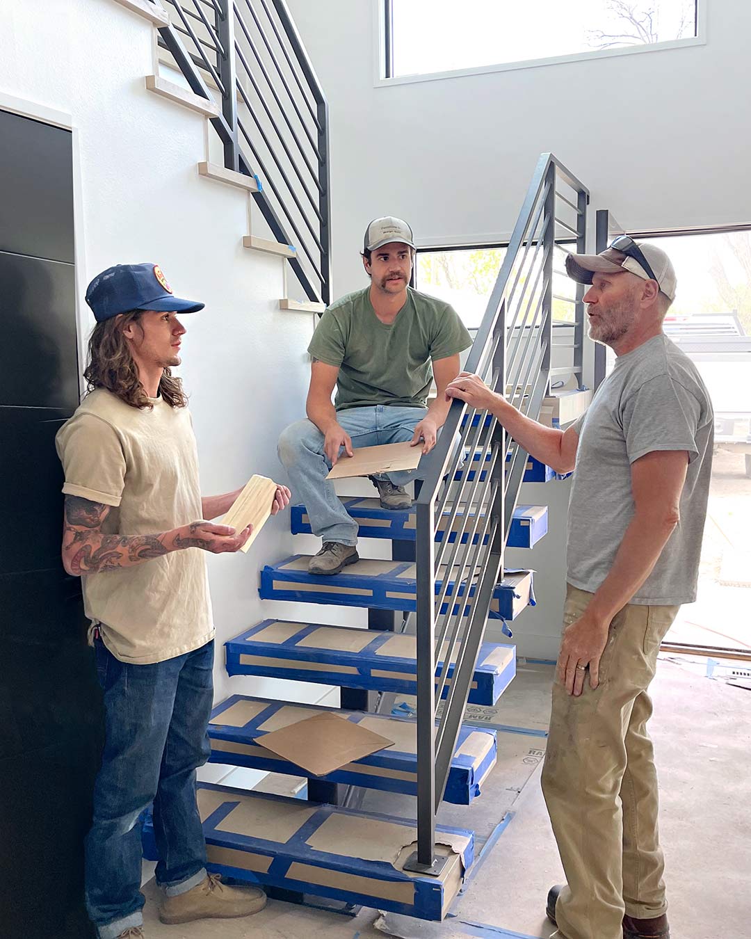 The Freestone Design-Build in house team is in the middle of a gameplan they are making while sitting on the custom built staircase in a mid-century pop-top home renovation project they are working on in Fort Collins Colorado off of Mulberry Street. 