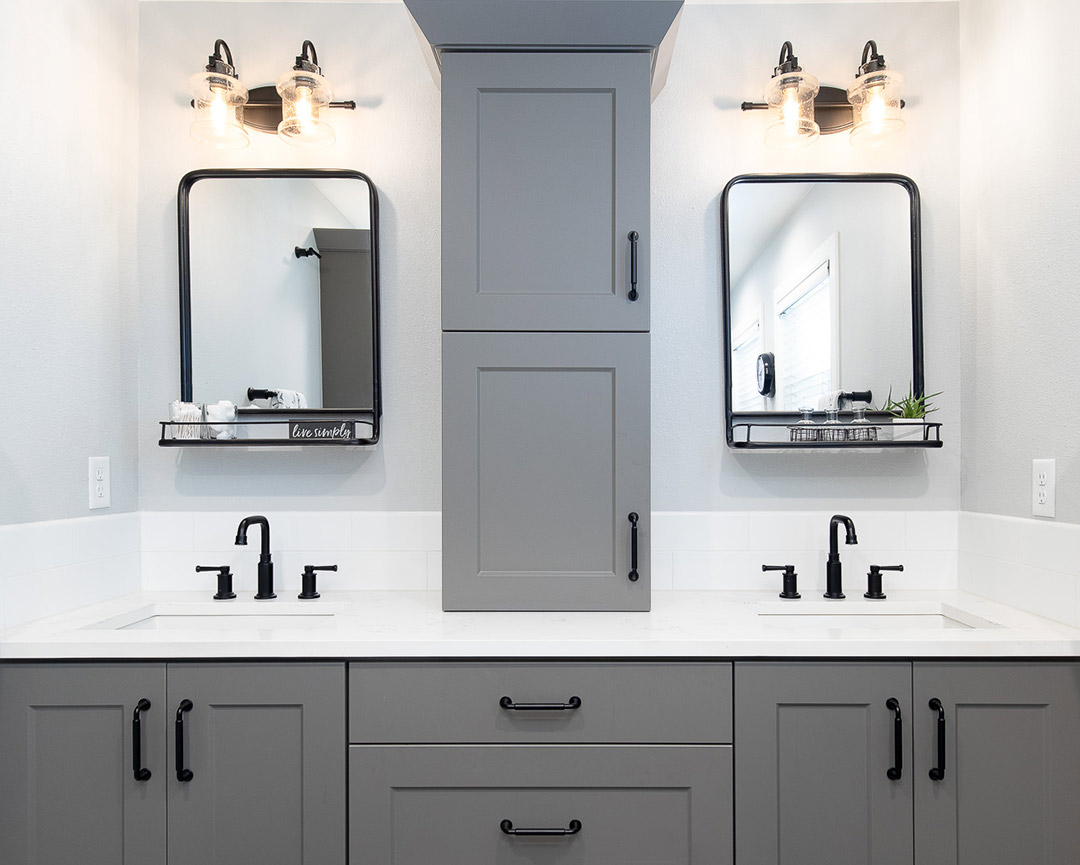 Modern double sink vanity with industrial farmhouse mirrors and pendant lights with matte black hardware, designed by Freestone Design-Build.