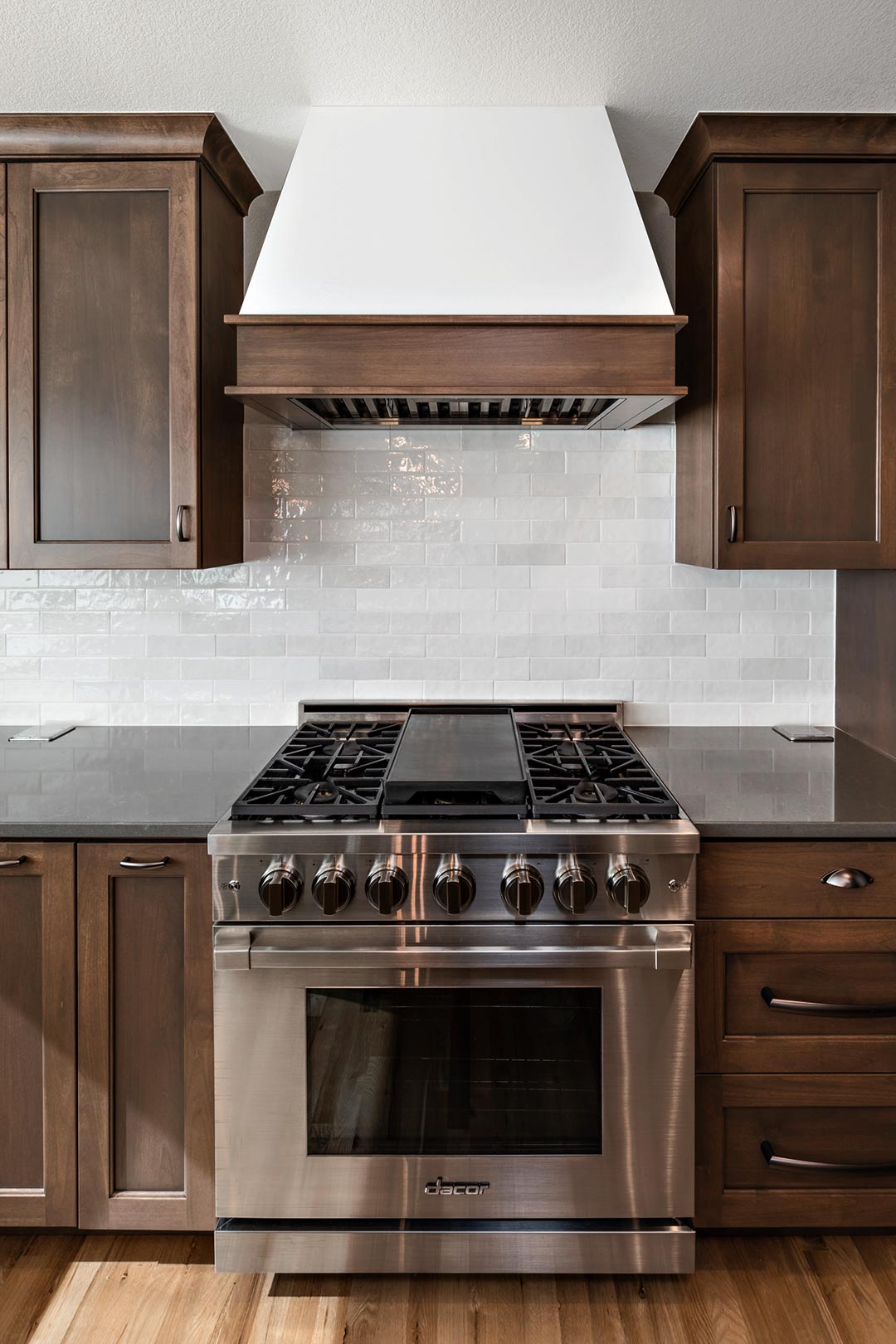 A beautiful range with a modern subway tiled backsplash and custom hood vent in Fort Collins Colorado