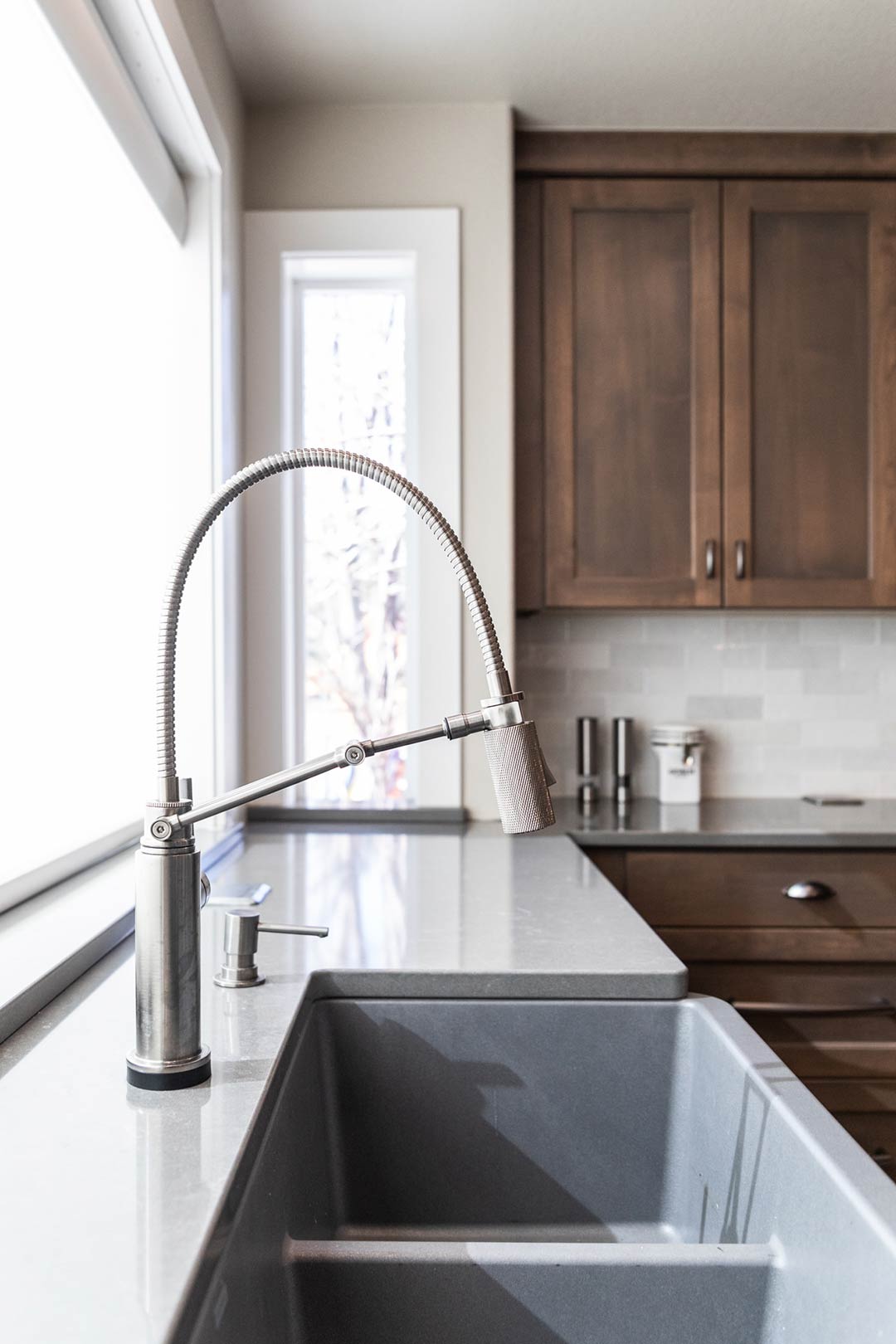 Detailed image of a transitional farmhouse style faucet over a modern apron sink in the Cliffrose Court project's kitchen