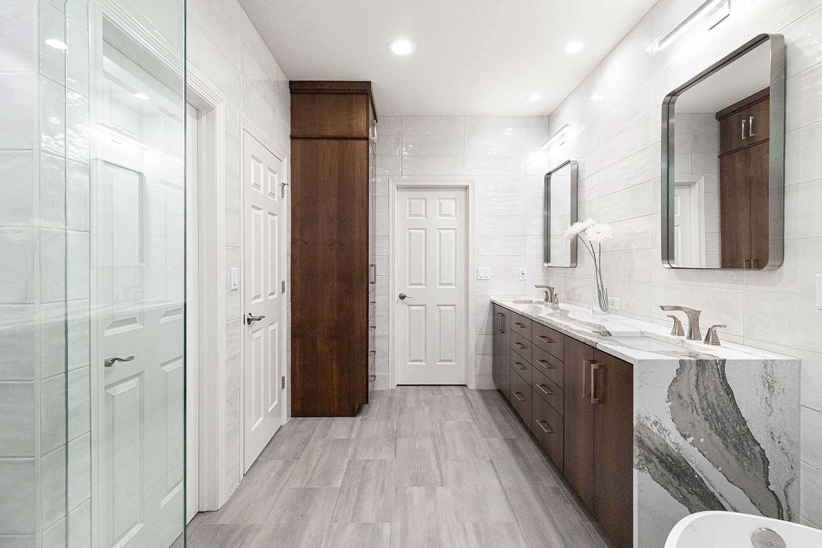 Custom cabinetry that adds storage space sits across from a double vanity in this contemporary bathroom renovation in Fort Collins Colorado.