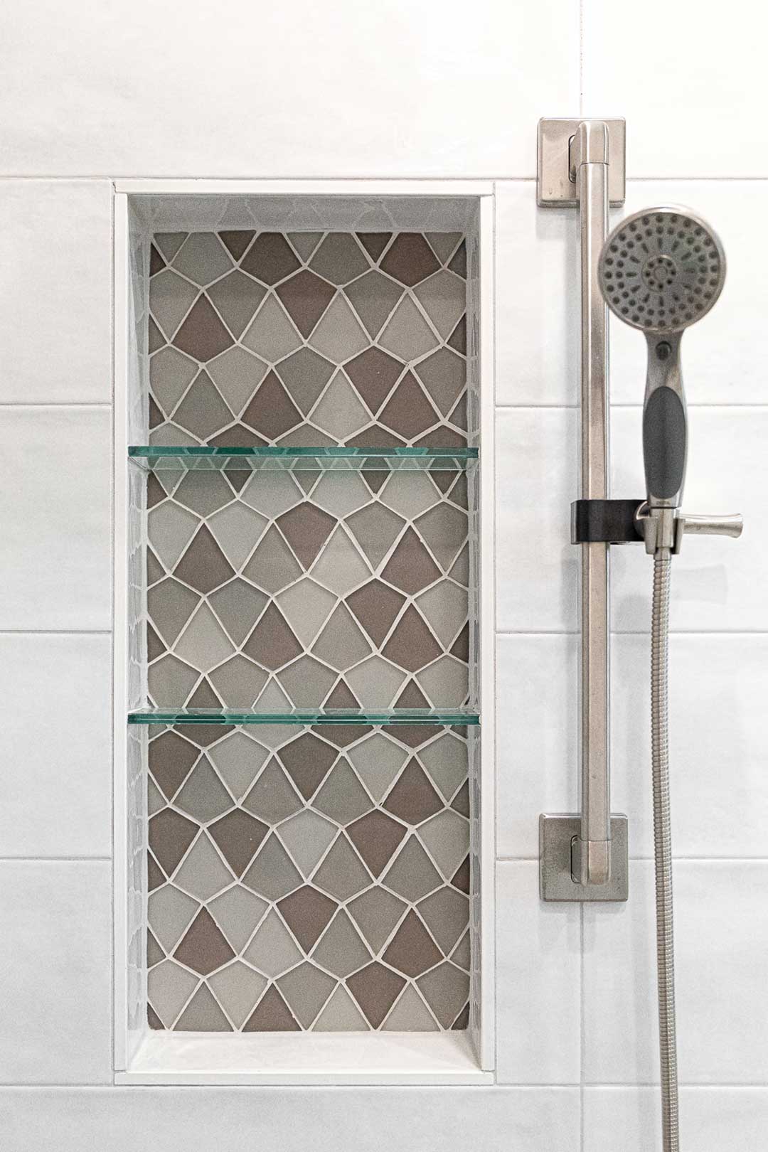 Detailed image of the modern shower rail and custom tiled shower niche installed by Freestone Design-Build