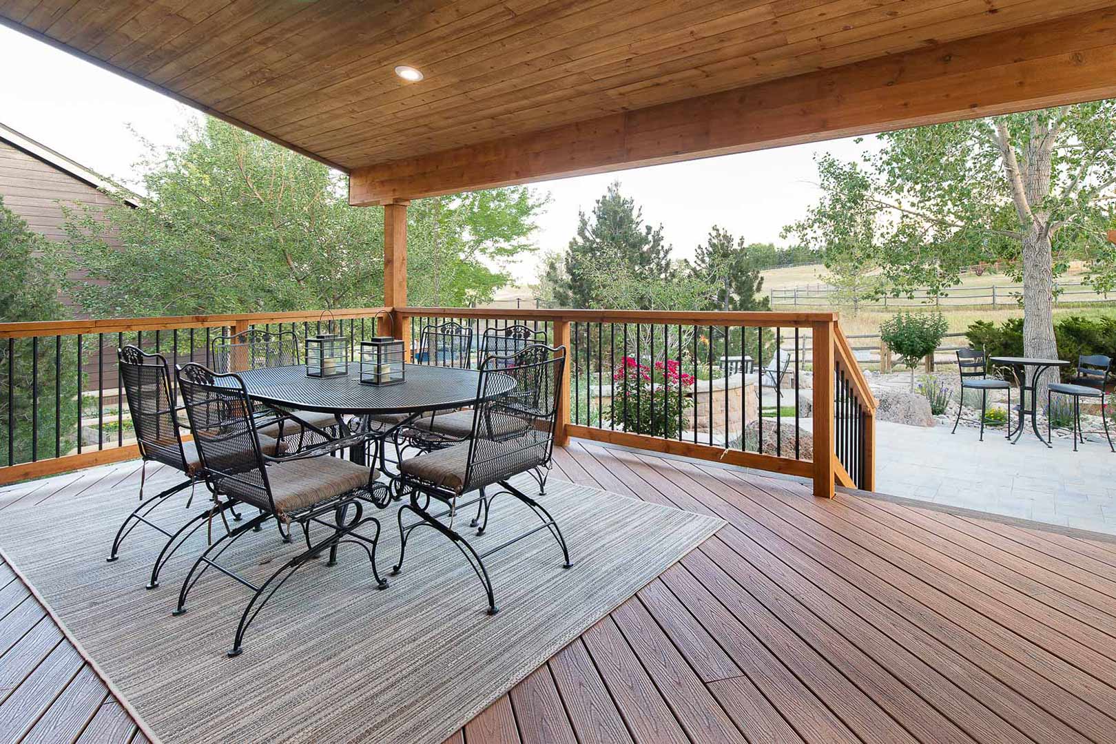 Dining table inside a custom covered deck showing integrated outdoor lighting nested in a tongue and groove ceiling. 
