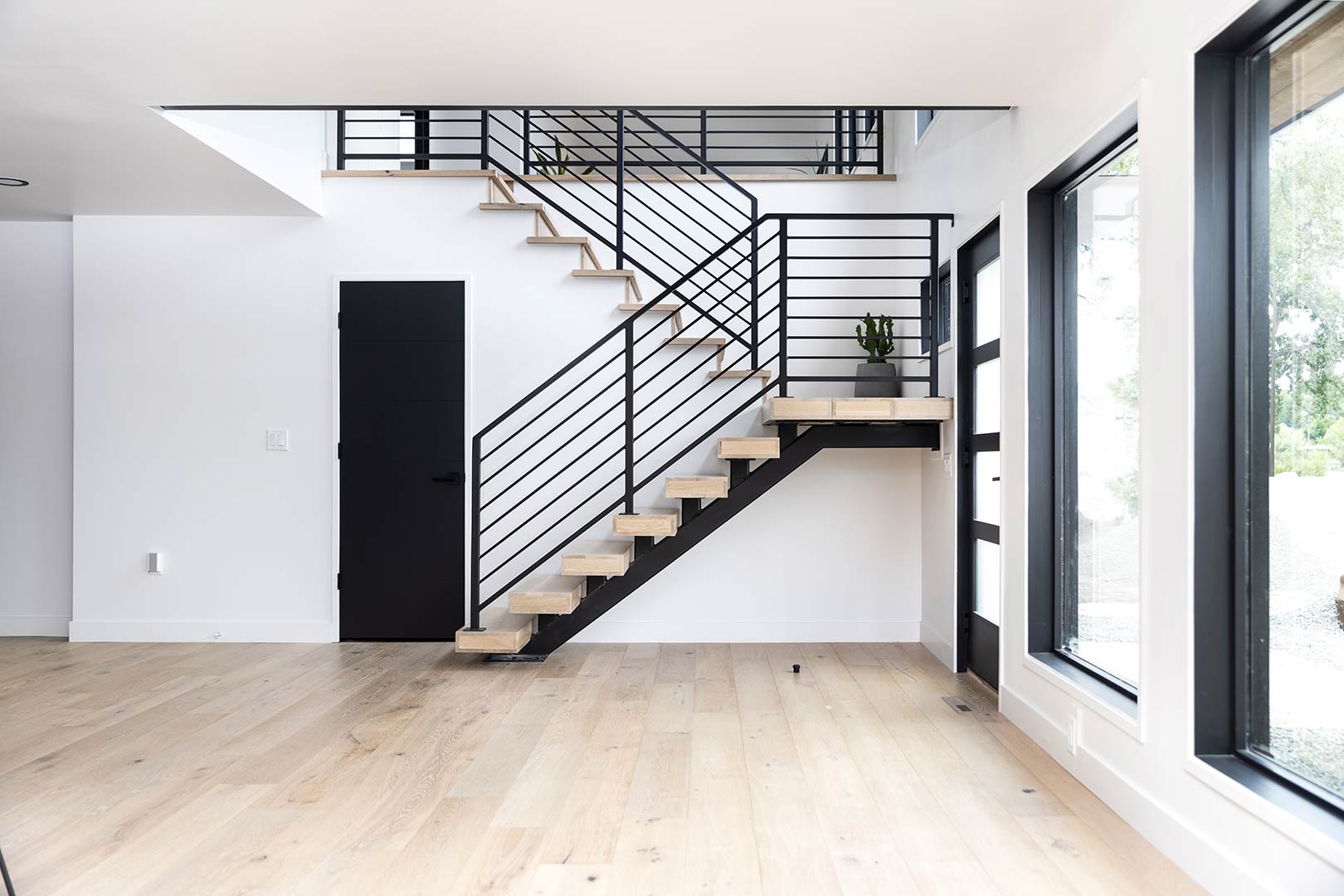 View of the stunning custom white oak floating stair-step staircase with a powder-coated steel handrail designed and installed by Freestone Design-Build