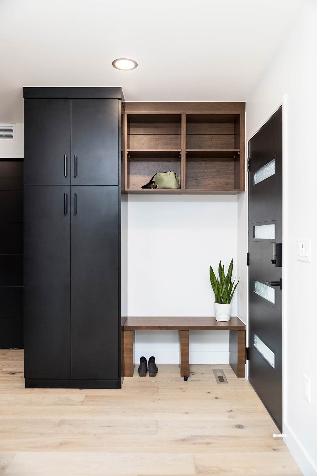 The mudroom at Mulberry Street recycled the family's original front door and was painted a matte black to match the built in cabinets and bench for additional storage.