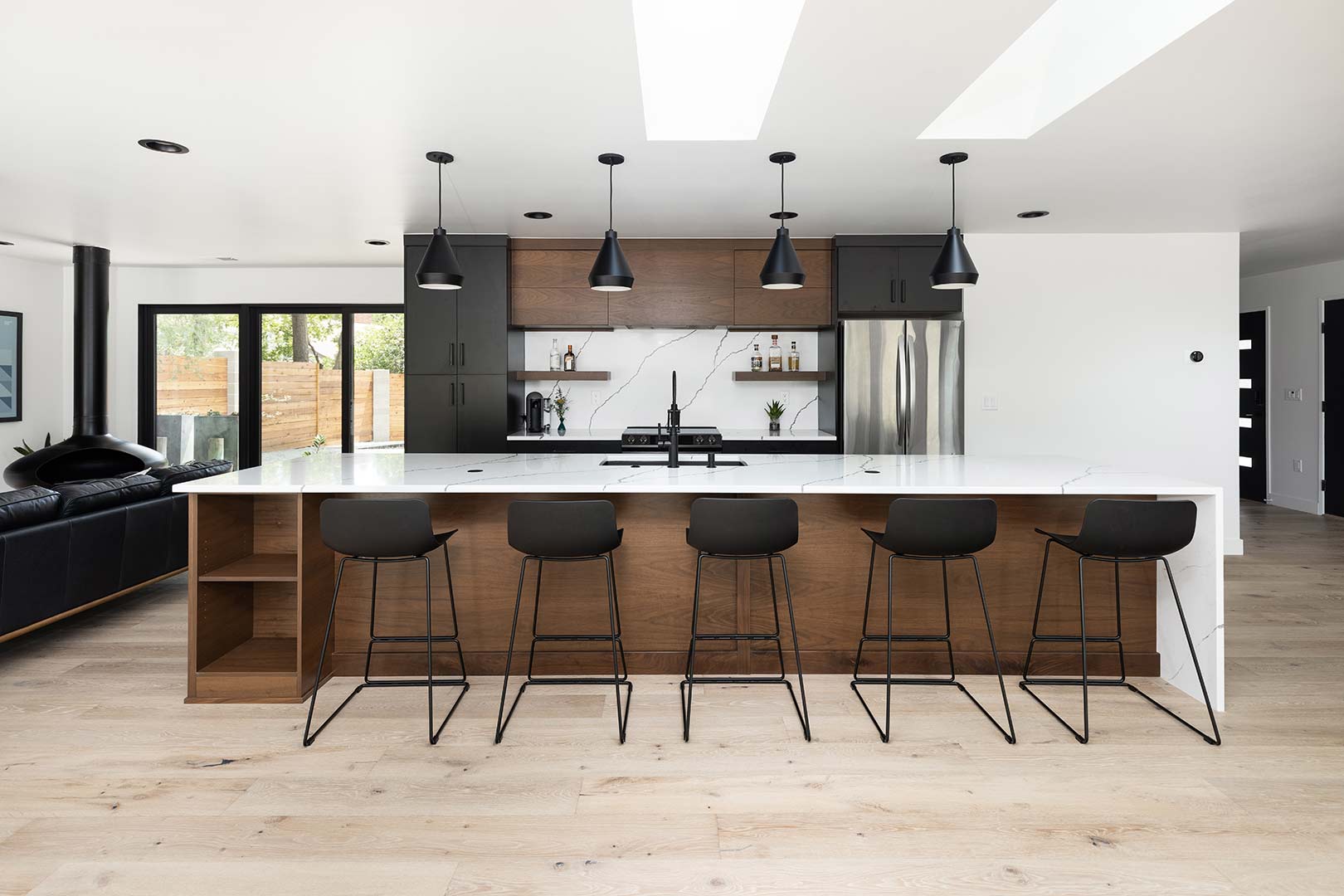Straight on view of the back of the five modern black barstools that over look the kitchen
