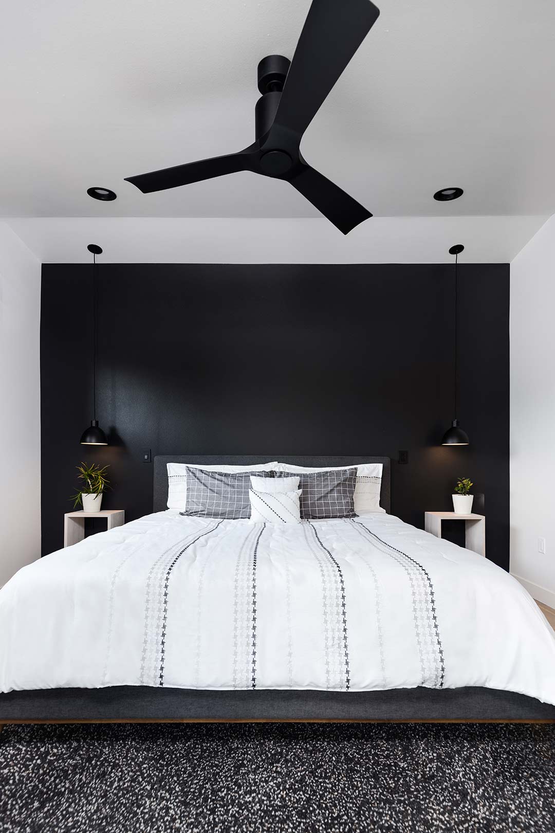 view of the master bedroom that shows the modern matte black fan, matte black can lights and matte black hanging pendant lights. 