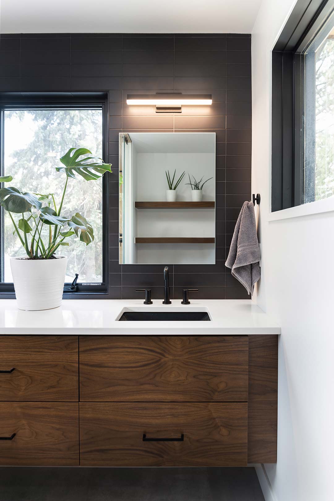Straight on view of the floating vanity with modern lighting and a plant that sits in front of the window that overlooks city park in Fort Collins Colorado
