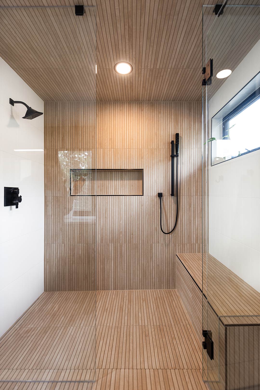 Modern walk in shower with a modern linear drain, frameless glass doors, and matte black hardware and fixtures, creating a spa-like retreat within the home.