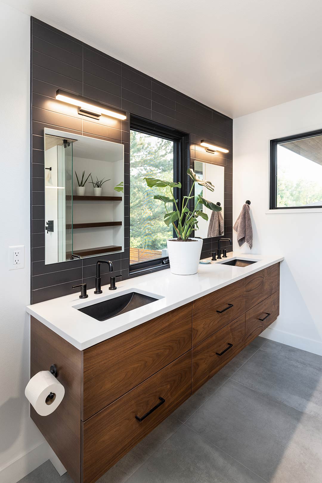 Custom floating vanity with a matte black tile black splash and concrete-look porcelain tile are made even more modern with matte black fixtures and pulls.