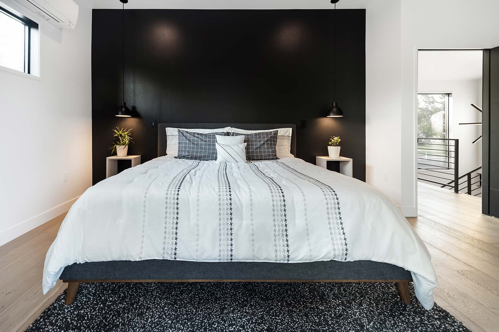 The master bedroom of this Fort Collins home remodel has a black accent wall with floating pendant lights and night stands