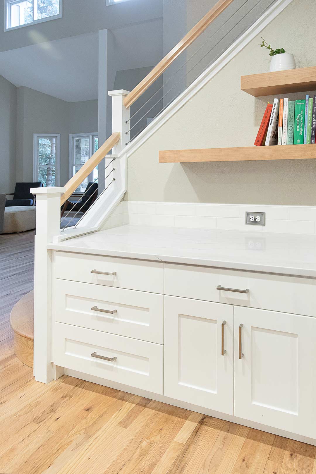 Custom built in cabinets and shelving that work seamlessly with the modern white oak and cable railing designed by Freestone Design-Build.