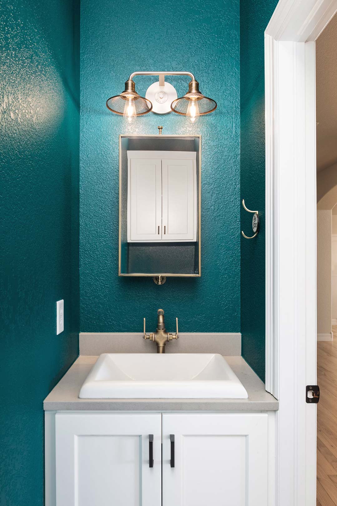 Hallway powder bath view showing the vibrant teal blue wall paint to match the kitchen cabinets nearby