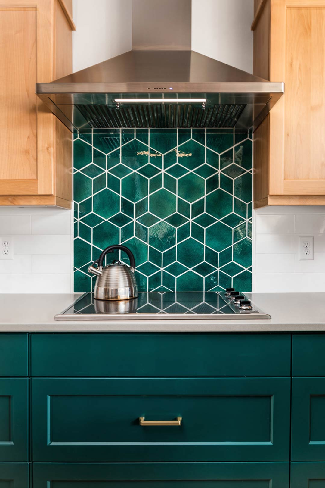A straight on view of the green tile mosaic backsplash that is over the oven and under the modern vent hood of this home renovation in Fort Collins Colorado.