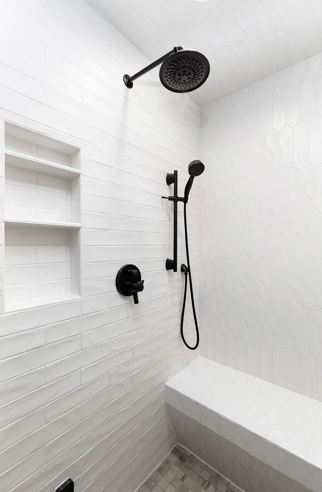 Modern walk in shower featuring a custom tiled shower niche installed by Freestone Design-Build
