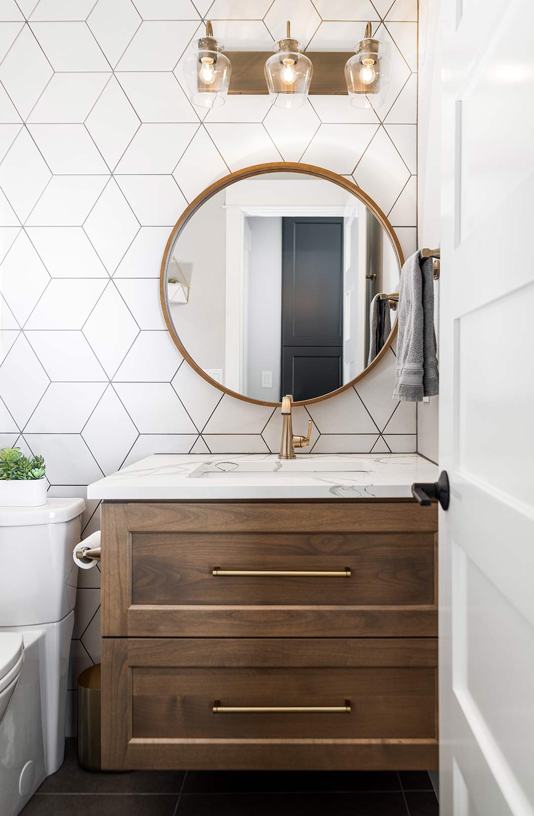 Transitional bathroom vanity with long modern brass pulls, a brass faucet and a modern brass light fixture.