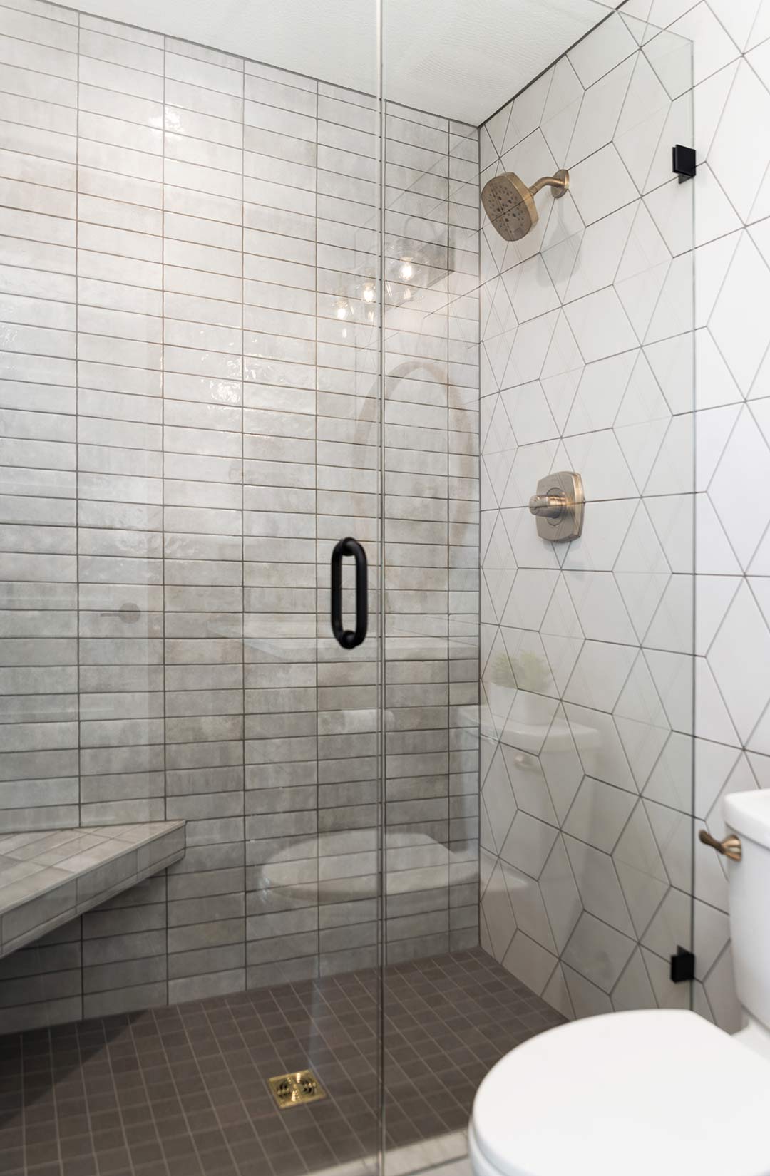 A walk in shower designed by Freestone Design-Build with frameless glass and a custom tile pattern