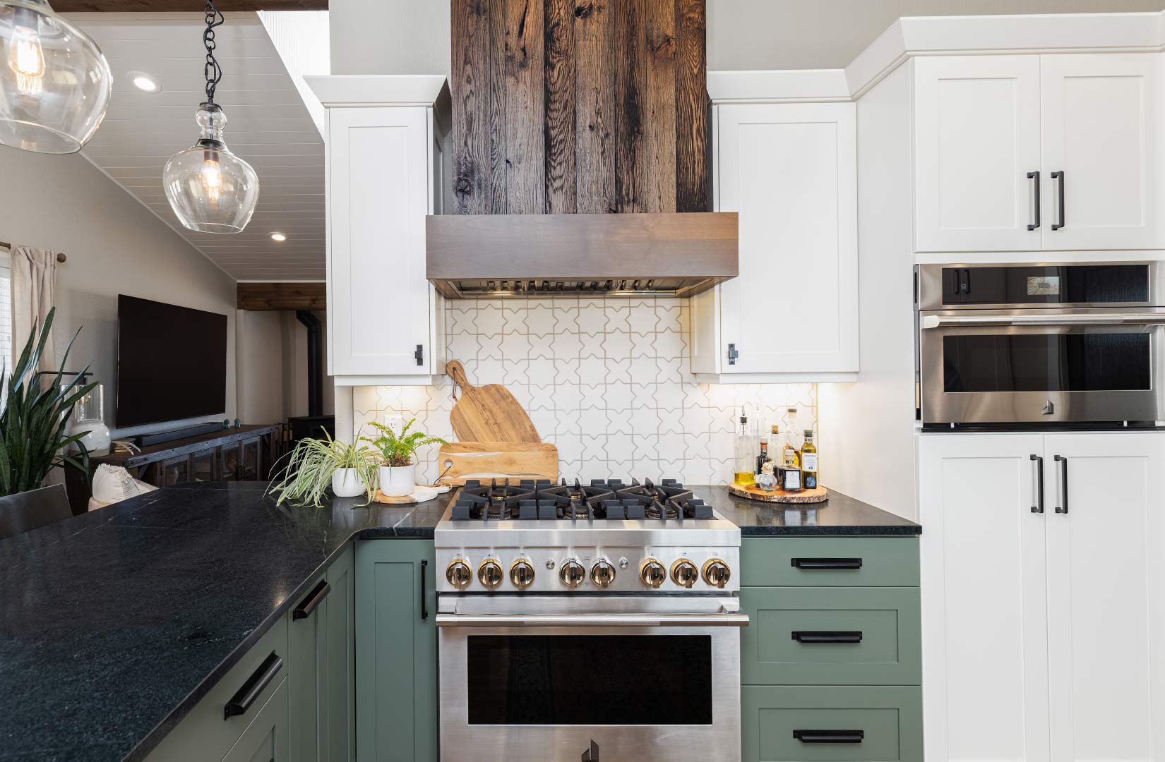 Industrial farmhouse style vent hood is featured over a modern stove with farmhouse style pendant lights picked out by Freestone Design-Build in Fort Collins Colorado.